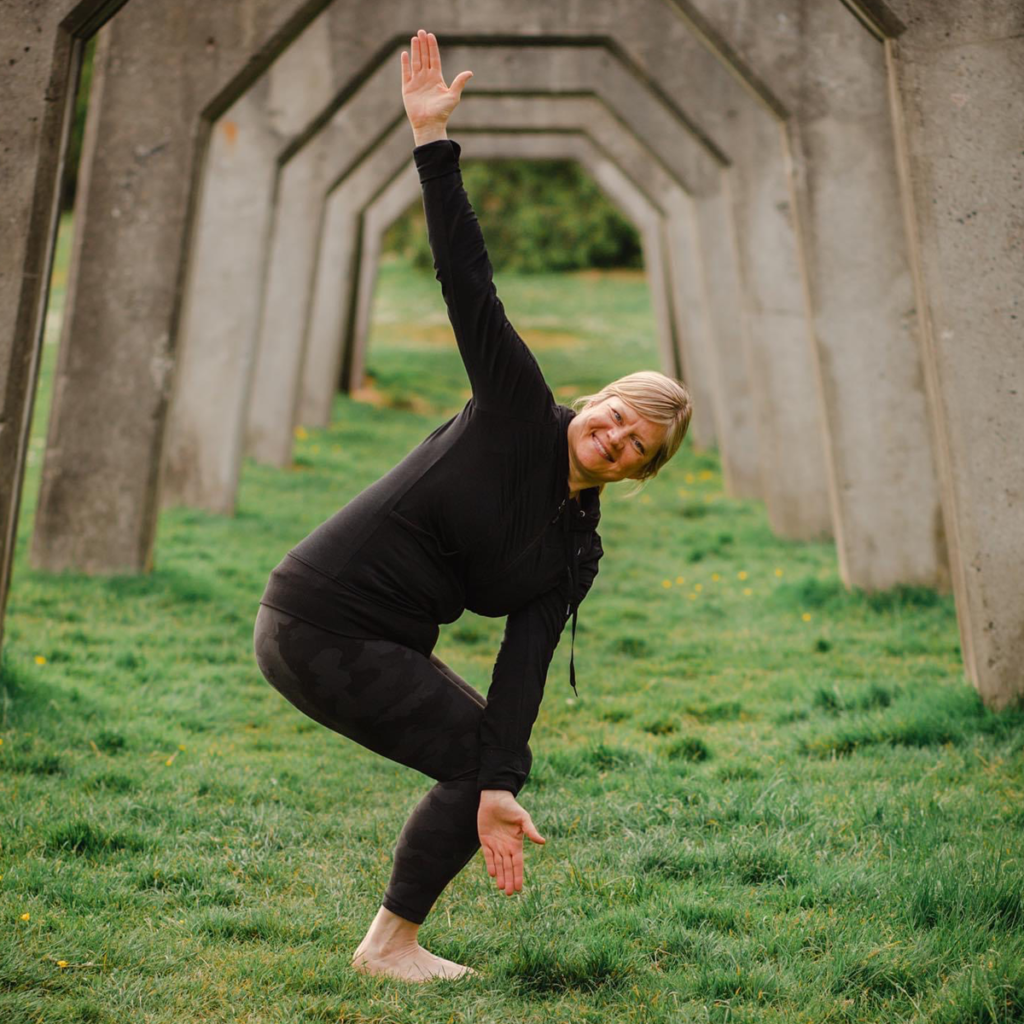 Christa doing yoga pose on green grass outside