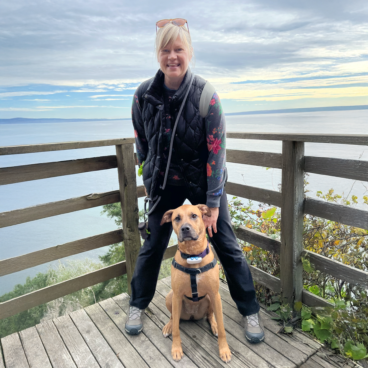 Christa standing with Rikka sitting between her legs on a beach bluff on Whidbey Island, with Puget Sound in the background.