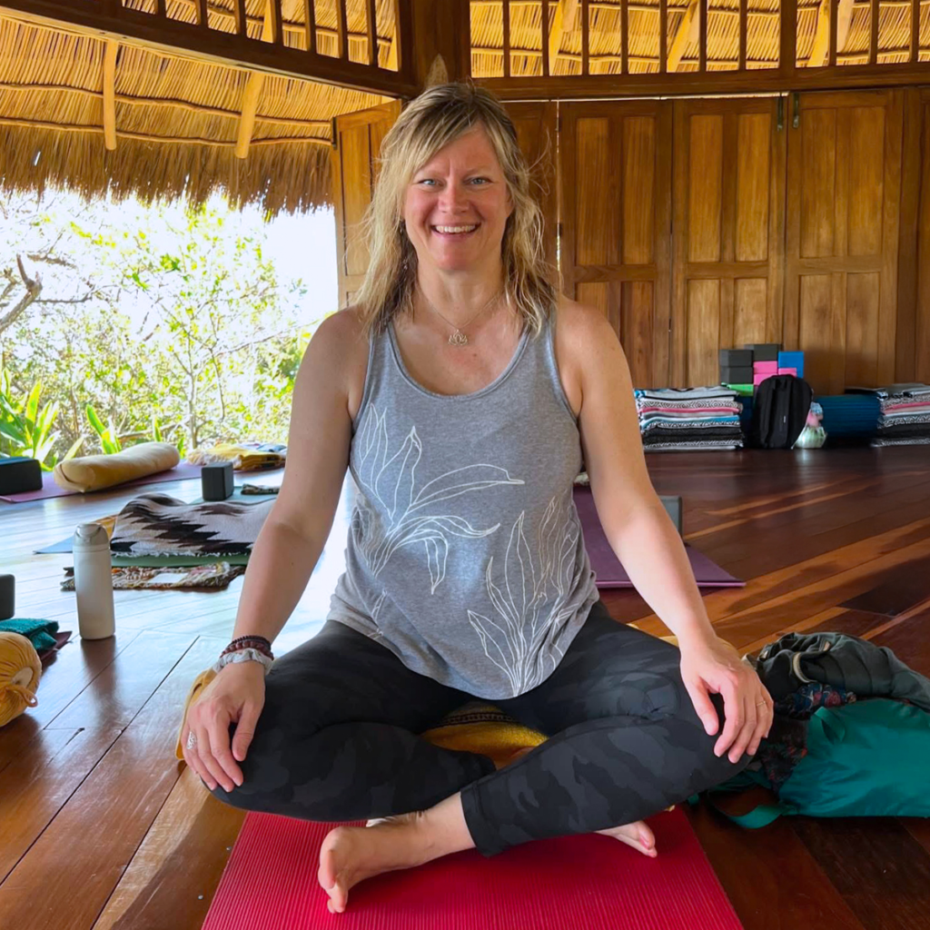 Christa sitting in lotus and smiling at camera at yoga retreat
